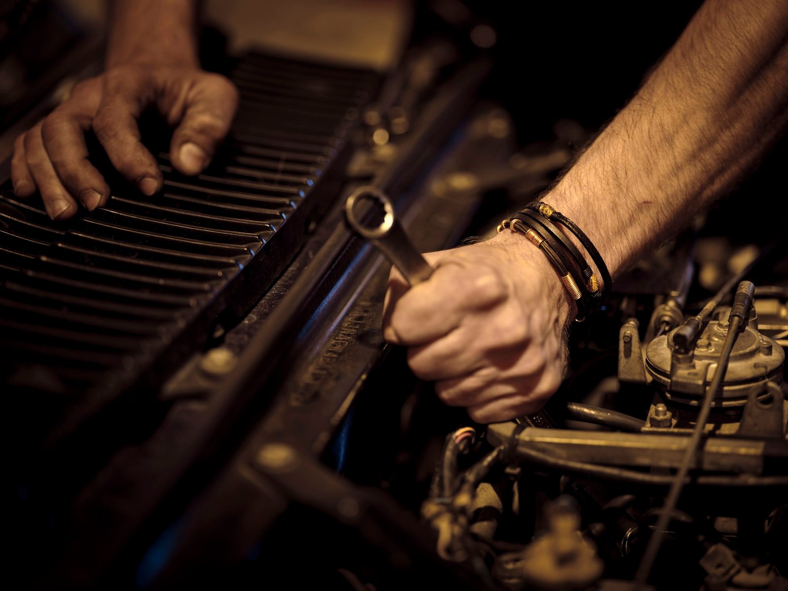 Mains d’un mécanicien travaillant sur un moteur avec une clé
