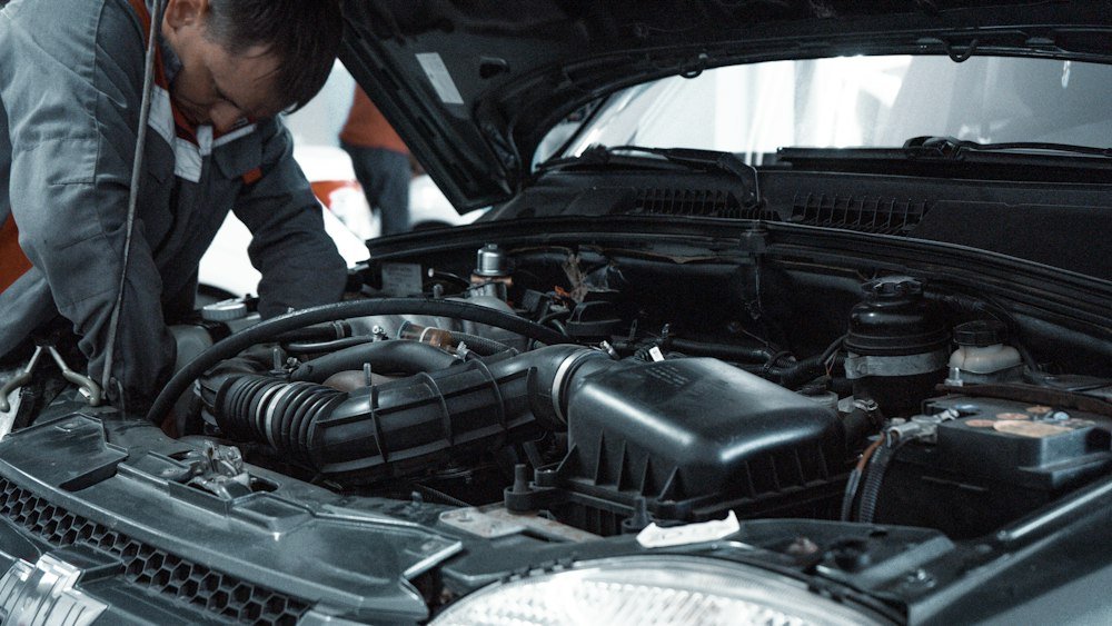 Mécanicien en uniforme inspectant le moteur d’une voiture